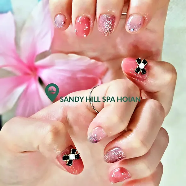 Pink glitter nails with black and white bow charms by Sandy Hill Spa